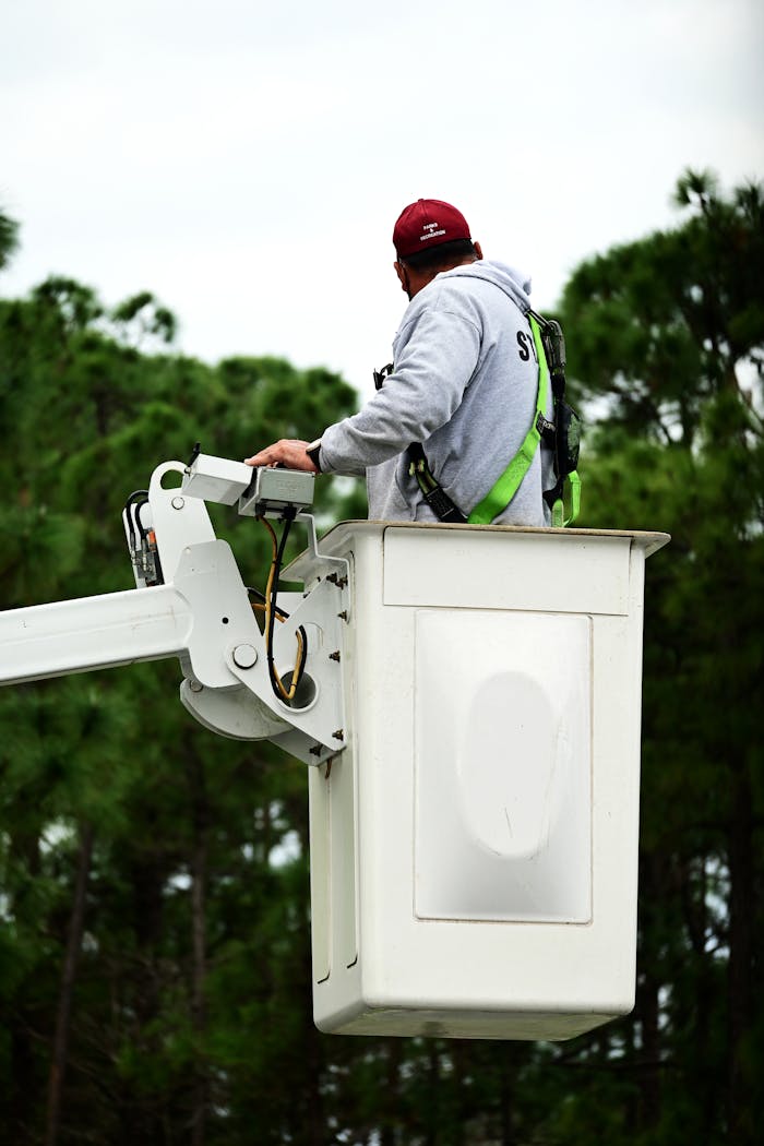 creative-02 A worker with safety gear operates a bucket truck outside, emphasizing safety and skill.