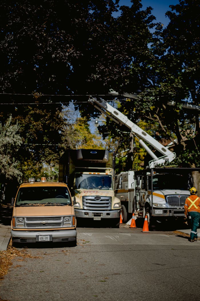 creative-03 Utility trucks with workers performing electrical maintenance on a leafy residential street.